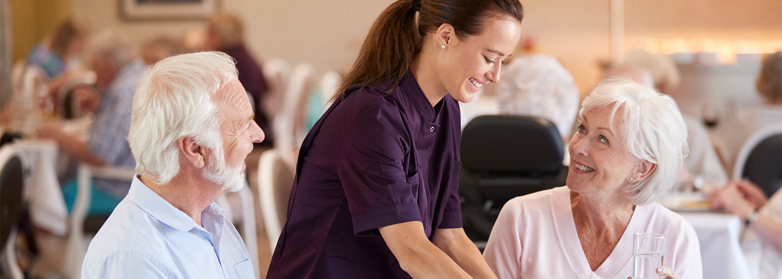 Senior couple in dining room with server.